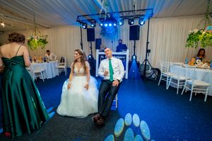 Wedding reception scene with formal attire and emerald green dress under blue lighting.