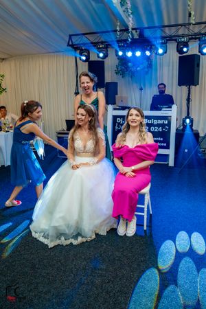 Wedding party members in coordinated blue and pink attire dancing during reception under dramatic lighting.