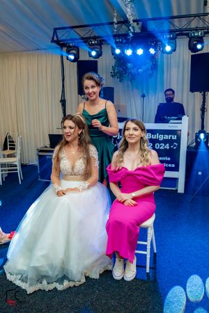 Wedding reception scene with attendees in formal attire seated under blue stage lighting.