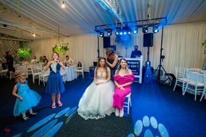 Wedding celebration with dancers in bright dresses performing under blue stage lights in a decorated reception tent.