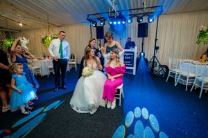 Reception venue with blue lighting showing wedding party and guests in formal attire.