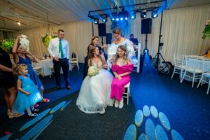 Wedding reception scene with blue lighting and white chairs showing dance floor activities.