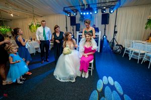 Wedding celebration with dynamic dance floor action under blue venue lighting.