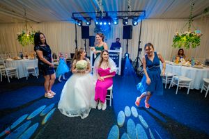 Wedding party dancing and celebrating under blue mood lighting at indoor reception.