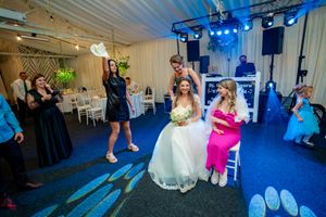 Wedding celebration with guests dancing under blue stage lights in an indoor venue.