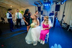 Indoor wedding venue with blue accent lighting and guests dancing during reception festivities.