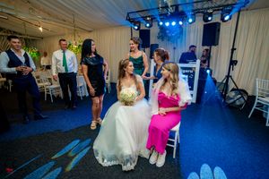 Wide view of a wedding reception venue with blue lighting and guests celebrating on the dance floor.