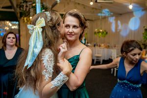 Lively wedding reception with guests dancing under decorative lighting and greenery.