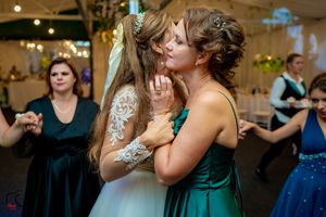 Guests dancing and celebrating at an indoor wedding reception with ambient lighting.