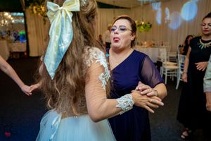 Wedding celebration with guests dancing under string lights and decorative greenery.