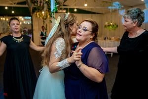 Wedding party dancing together in an indoor venue with festive lighting and decorations.