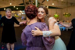 Joyful dancing and celebration at a wedding reception with purple and white decor.