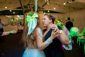 Wedding celebration showing guests dancing in venue decorated with string lights and colored uplighting.