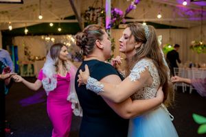 Energetic wedding reception scene with guests dancing under colorful lighting and decorative elements.