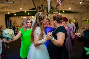 Wedding reception venue with string lights and purple uplighting as guests dance and celebrate.