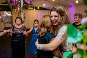 Wedding celebration showing guests dancing under string lights with purple and green accent lighting.