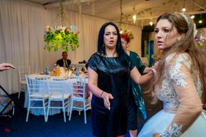 Festive wedding reception with guests enjoying themselves under decorative lighting and floral arrangements.
