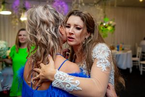 Emotional moment captured during wedding reception with guest in vibrant blue dress.