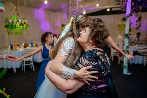 Tender moment shared during wedding reception with decorative lighting and floral arrangements.