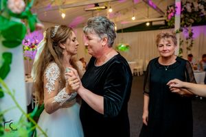 Intimate dance moment at wedding reception with decorative floral elements and purple lighting.