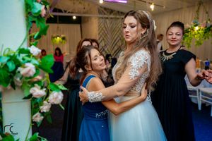Wedding guests dance together at a reception decorated with green floral accents and purple lighting.