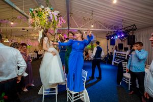 Wedding celebration in a tent venue with hanging greenery and ambient lighting.