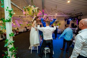 Wedding reception venue decorated with green vines and colorful lighting for evening celebration.