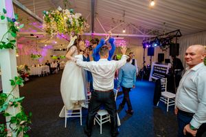 Wedding reception dance floor with decorative lighting and floral arrangements along the walls.