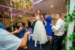 Festive wedding reception with colorful lighting and guests celebrating on the dance floor.
