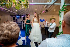 Indoor wedding celebration with decorative lighting and greenery showing guests enjoying the dance floor.