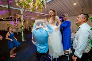 Energetic dance party at wedding reception with guests in formal attire under purple lighting.