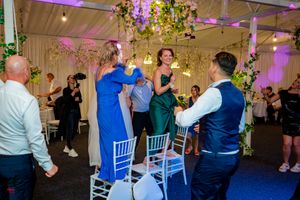 Wedding reception dance floor filled with guests under decorative lighting and floral installations.