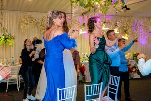 Guests enjoying a lively dance party at an indoor wedding reception with purple ambient lighting.
