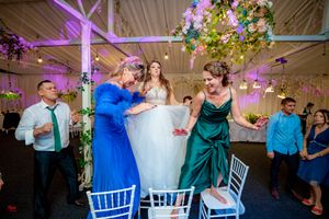 Indoor wedding celebration with elegant white chairs and dramatic purple lighting design.