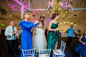 Festive wedding celebration with guests in blue and green attire under decorative lighting.