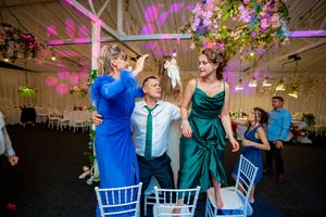 Wedding guests dancing and enjoying festivities under purple mood lighting and floral decor.