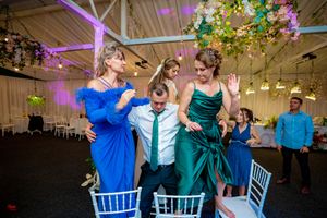 Wedding reception venue with purple uplighting and hanging floral decorations during a celebration.