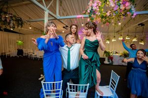 Wedding celebration with colorful lighting and decorative floral arrangements in an indoor venue.