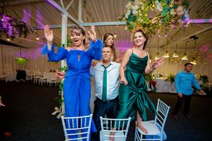 Reception guests in bright blue and emerald dresses enjoying festivities.
