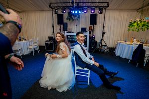 Wedding celebration space with dramatic blue lighting and white chair arrangements.