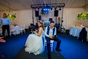 Reception hall decorated with white linens and blue lighting for evening celebration.