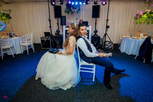 Wedding reception space with theatrical lighting and white decor against blue carpet.