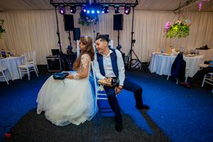 Wedding venue interior showing stage lighting setup and white draped walls with blue flooring.