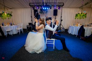 Wedding celebration venue featuring dramatic blue lighting and white fabric ceiling decor.
