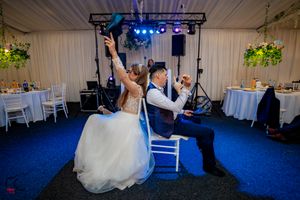 Wedding venue decorated with white drapes, blue accent lighting, and floral arrangements.