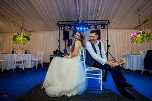 Wedding celebration space featuring blue stage lighting, white decor, and floral arrangements.