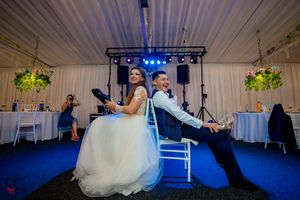 Wedding reception venue with blue lighting and white drapes showing stage setup and dance floor area.