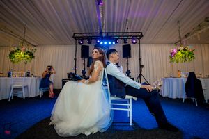 Wedding reception venue decorated with dramatic purple lighting and entertainment setup.