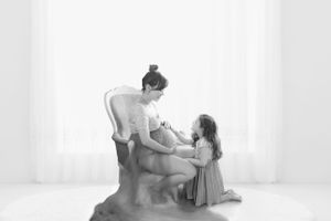 A tender black and white portrait of a mother and child sharing an intimate moment in a minimalist setting.