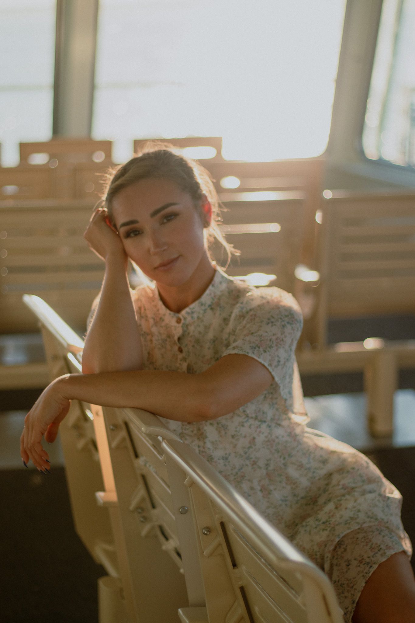 Golden hour portrait in white lace dress leaning on railing.